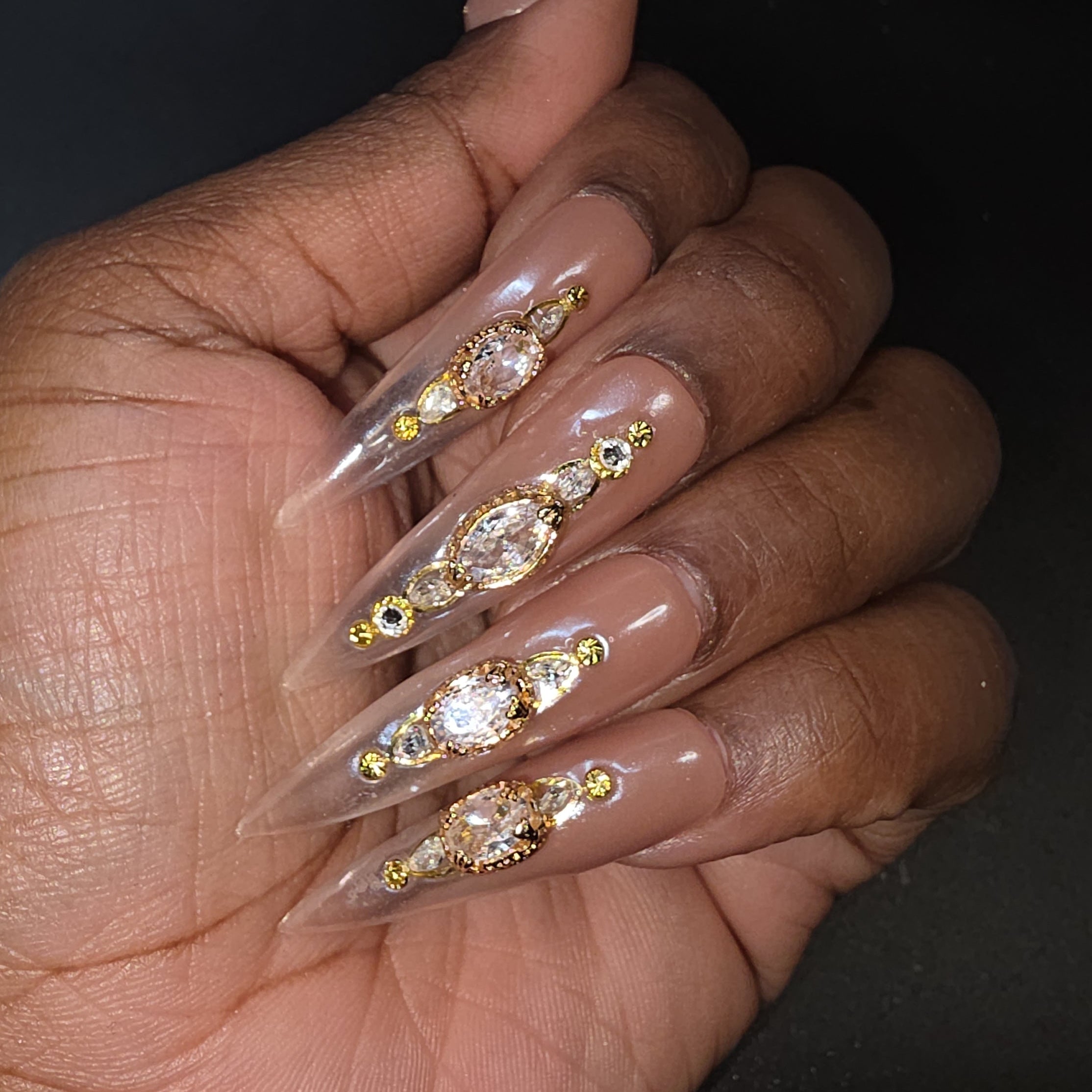 Hand with long, decorated nails on a dark background