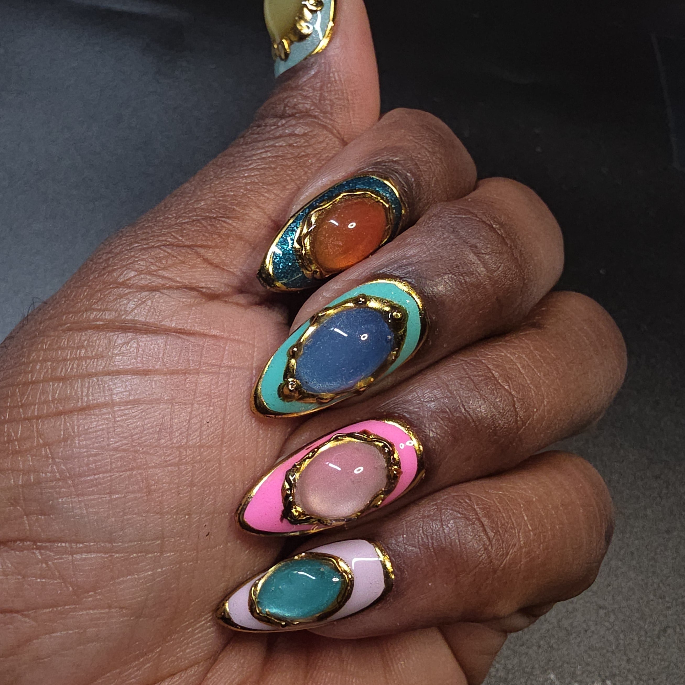 Hand with multicolored nail art on a dark background