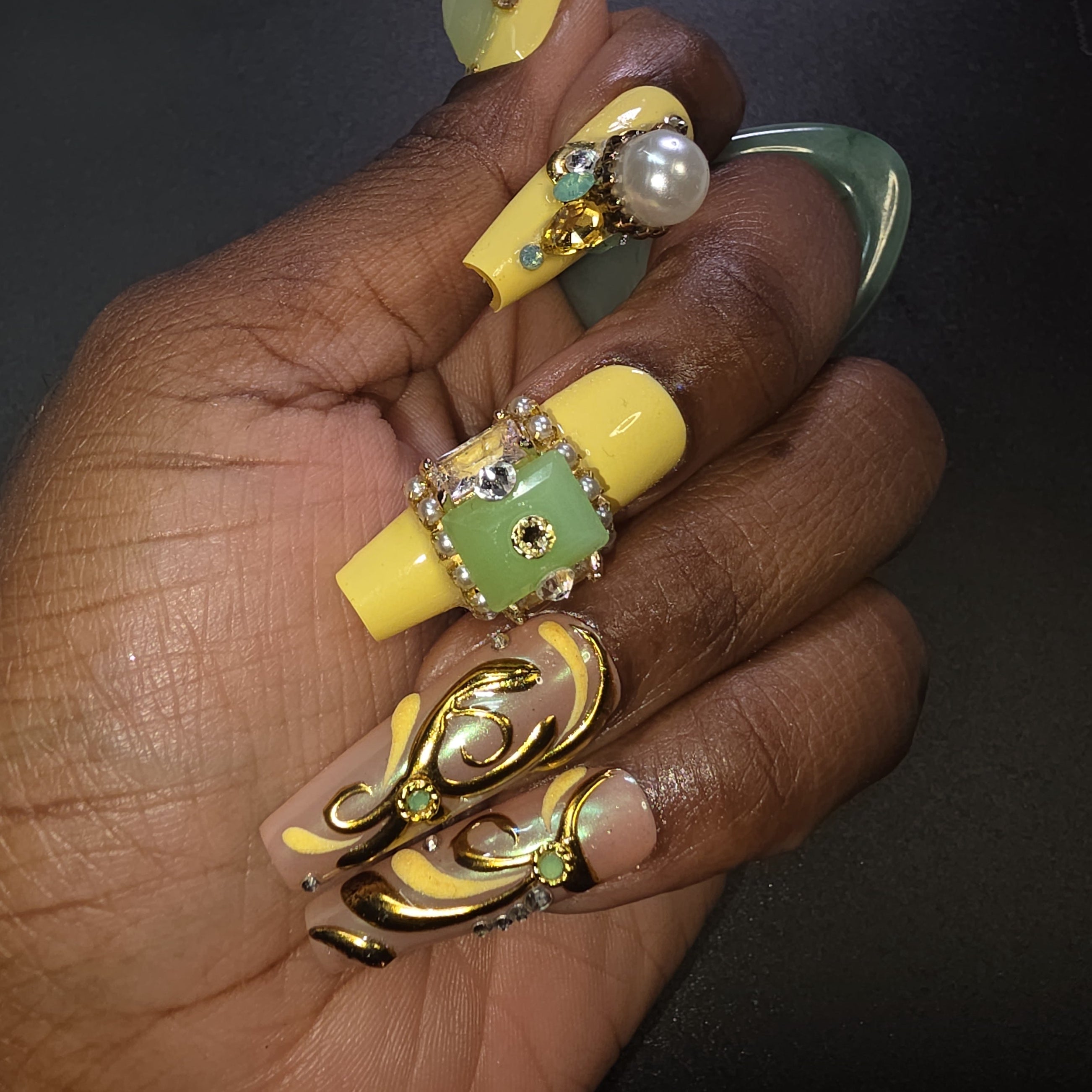 Hand with yellow and green nail art on a dark background