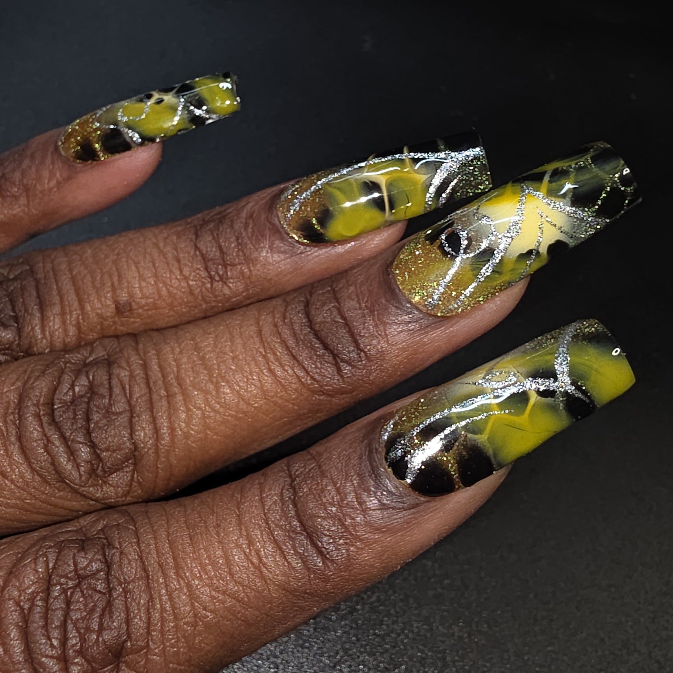 Hand with yellow and black nail art on a dark background