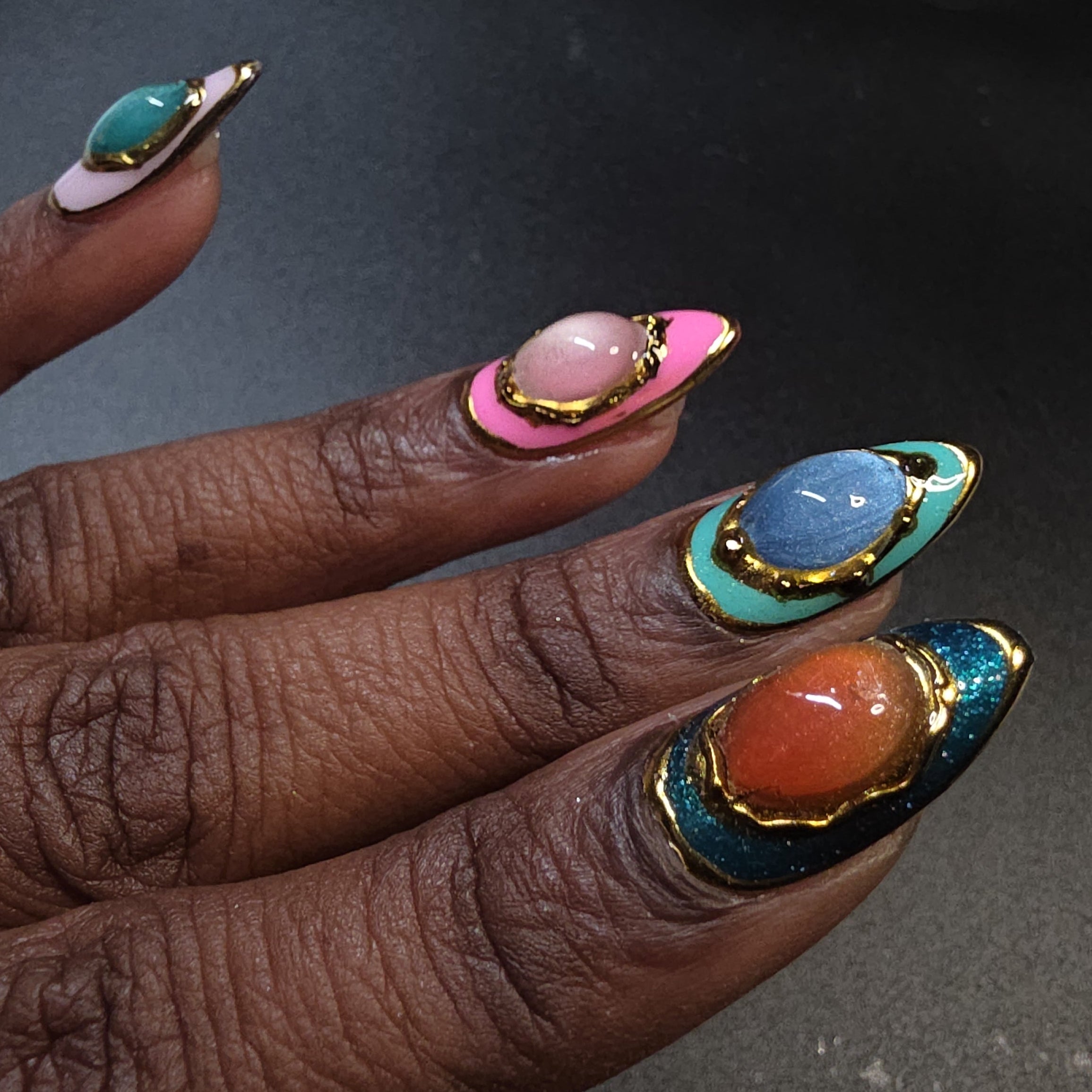 Close-up of a hand with colorful nail art on a dark background